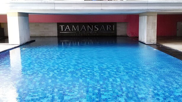 A swimming pool with a sign reading "TAMANSARI SUDIRMAN Executive Residence".