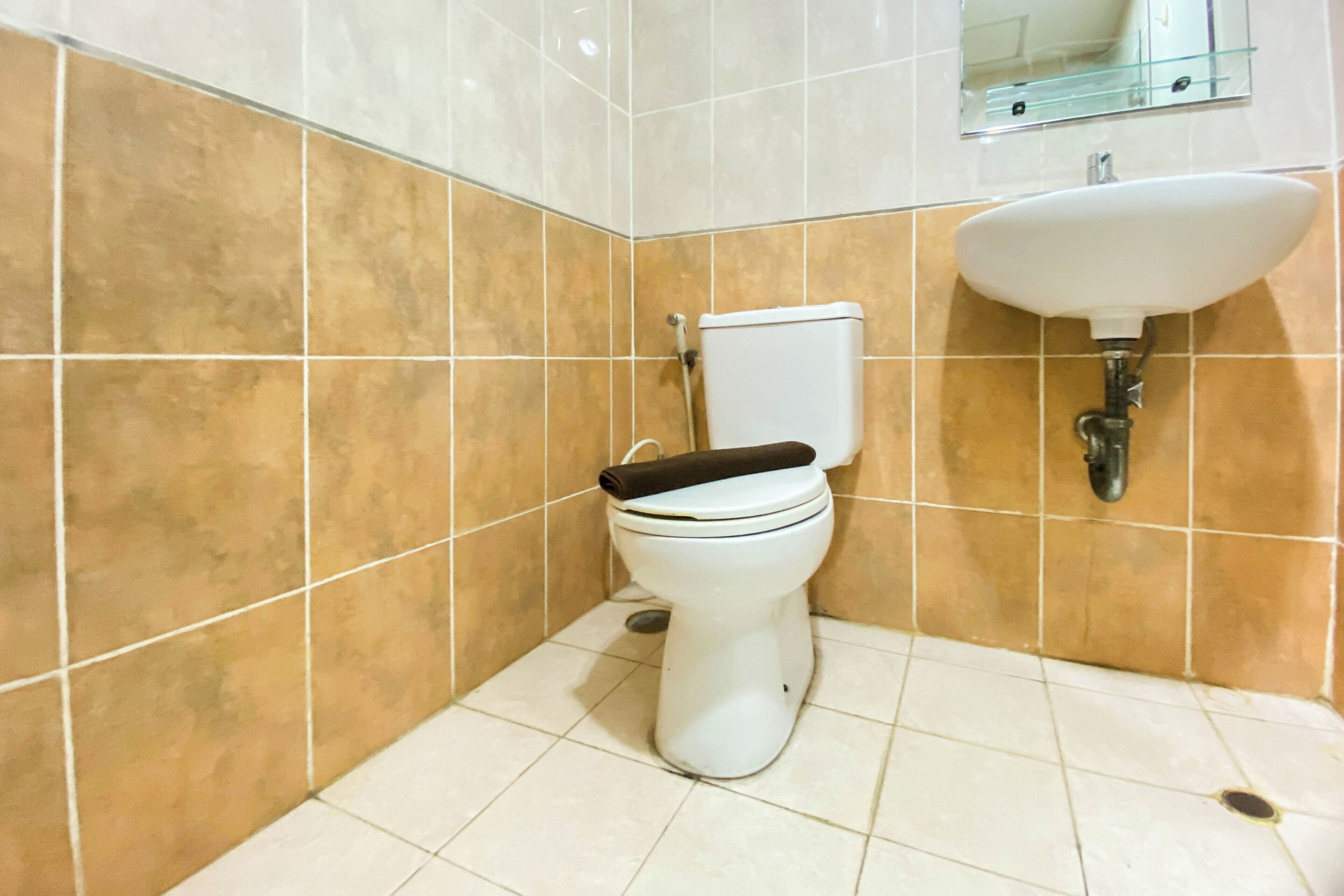 A bathroom with a toilet, sink, and tiled walls.