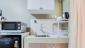 A compact kitchen with a microwave, sink, and cabinets. - Comfy And Modern Studio (No Kitchen) At Loftvilles City Apartment (South Tangerang)