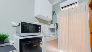 A compact kitchen with a microwave, refrigerator, and a small sink. - Comfy And Modern Studio (No Kitchen) At Loftvilles City Apartment (South Tangerang)