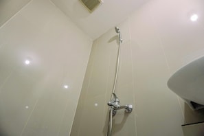 Ein Badezimmer mit Dusche, Waschbecken und Deckenlüfter.
