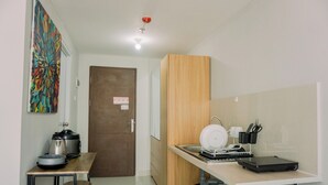 A compact kitchen with a wooden cabinet, a sink, a countertop, and a small table with stools. - Modern Classic Studio At Majestic Point Serpong Apartment (Gading Serpong)