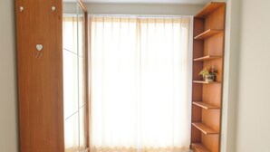 Una habitación con un armario de madera, una puerta de cristal y una estantería de madera.