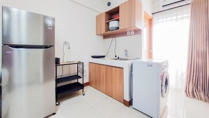 Una cocina compacta con refrigerador de acero inoxidable, horno empotrado, microondas, pileta y lavadora.