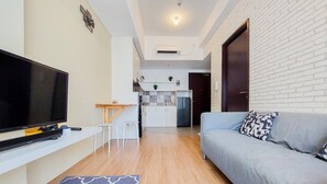 A modern living room with a flat-screen TV, a grey sofa, and a patterned rug. - Strategic And Restful 1Br At Casa De Parco Apartment (South Tangerang)