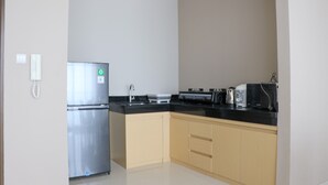 A kitchen with a stainless steel refrigerator, a black countertop, and beige cabinets. - Spacious And Comfy 3Br Ciputra International Apartment (Jakarta)