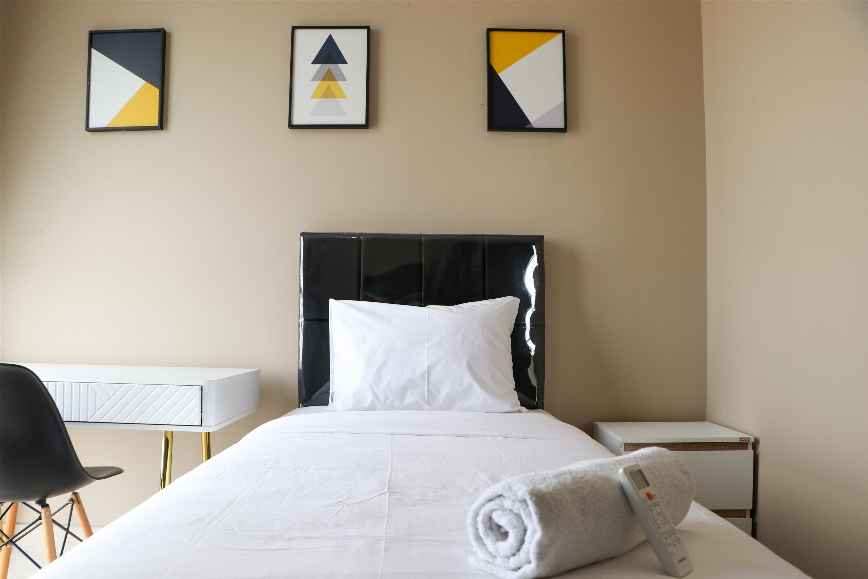 Habitación de hotel con cama, escritorio y silla. Hay tres cuadros en la pared.