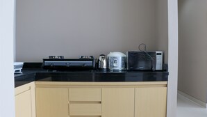 A kitchen with a black countertop, a rice cooker, a microwave, and a coffee maker. - Spacious And Comfy 3Br Ciputra International Apartment (Jakarta)