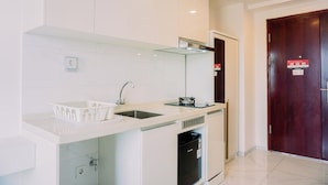 A modern kitchen with white cabinets, a stainless steel sink, a dishwasher, and a built-in oven. - Warm And Simply Studio Room Sky House Alam Sutera Apartment (Tangerang)