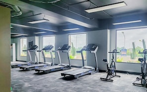 Ein Fitnessraum mit Laufbändern, Fahrrädern und Rudergeräten.