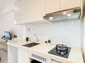 A modern kitchen with a stainless steel range hood, a double sink, and a built-in dishwasher. - Warm And Simply Studio Room Sky House Alam Sutera Apartment (Tangerang)
