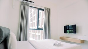 A hotel room with a bed, a TV, and a window with curtains. - Warm And Simply Studio Room Sky House Alam Sutera Apartment (Tangerang)