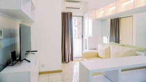 Una habitación de hotel moderna con televisor de pantalla plana, escritorio, sofá y un ventanal con cortinas.