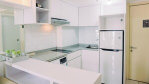 Una cocina moderna con armarios blancos, horno empotrado, refrigerador y encimera de granito.