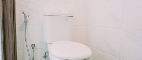A bathroom with a toilet, a shower, and a toilet paper holder.
