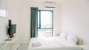 A hotel room with a bed, a TV, a desk, and a window with curtains. - Wonderful And Strategic Studio Apartment Sky House Alam Sutera (Tangerang)