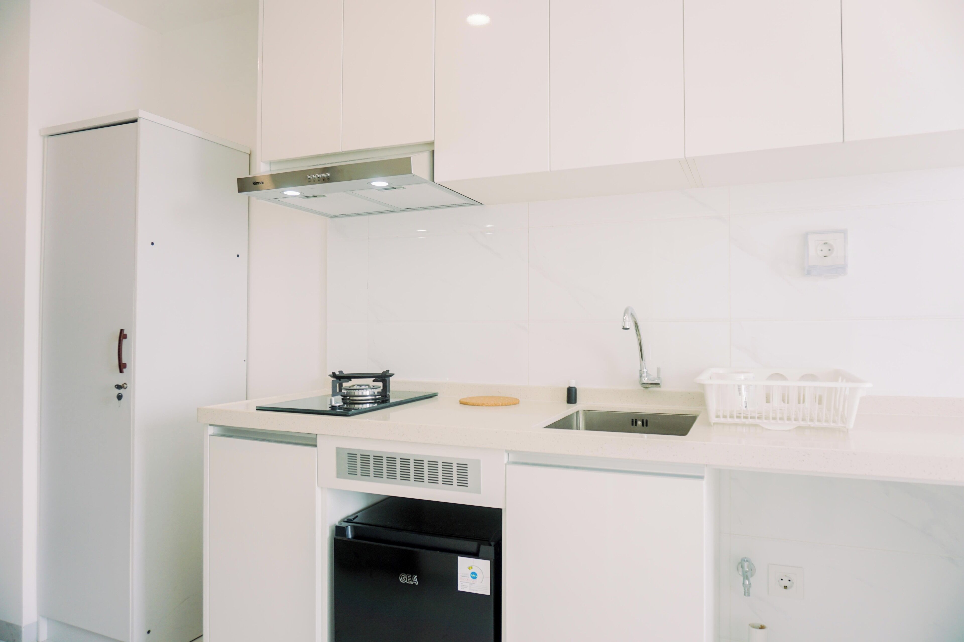 Une cuisine moderne avec des armoires blanches, une hotte de cuisinière en acier inoxydable, un lave-vaisselle intégré et un évier avec un robinet.