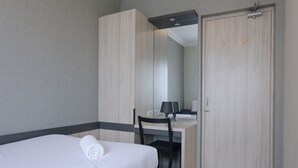 Una habitación de hotel con cama, escritorio, silla, espejo y armario.