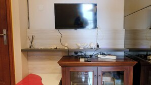 Una cocina moderna con un televisor de pantalla plana montado en la pared, armarios de madera y un sillón rojo de acento.