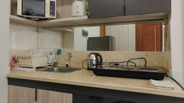 Una cocina con microondas, cocedor de arroz y hervidor eléctrico sobre la encimera.