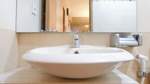 Un baño con un lavamanos blanco, un espejo y un dispensador de toallas.