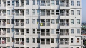 A multi-story residential building with balconies, air conditioning units, and a uniform exterior design.