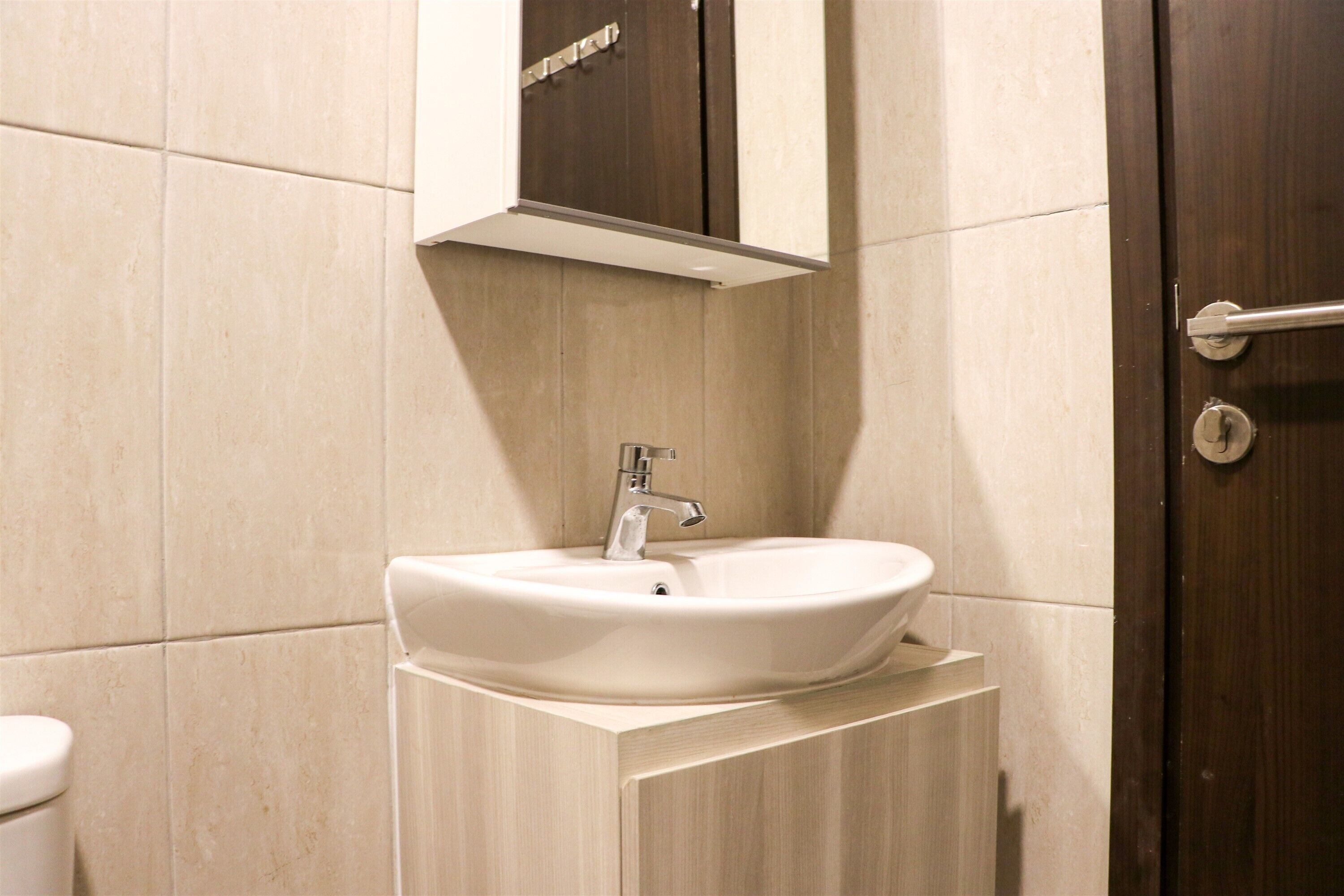 Une salle de bain avec un lavabo blanc, un meuble en bois et une porte en bois foncé.