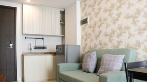 A compact living space with a kitchenette, a sofa with two pillows, and a dining table.