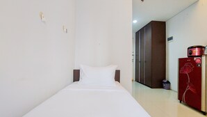 Una habitación de hotel con una cama individual, un armario y un refrigerador.
