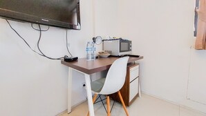 Una kitchenette pequeña con microondas, dispensador de agua y un televisor de pantalla plana montado en la pared.