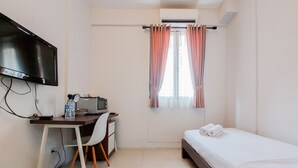 Una habitación pequeña y limpia con cama, escritorio con computadora y televisión.