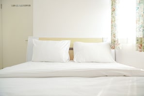 A neatly made bed with white linens and a wooden headboard. - Nice And Modern 2Br At Green Pramuka City Apartment (Jakarta)