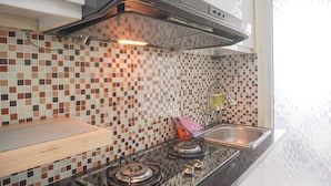 A kitchen with a tiled backsplash, a gas stove, a stainless steel sink, and a hood above the stove.