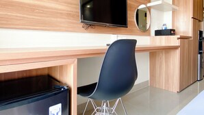 Een moderne keuken met een houten aanrecht, een zwarte stoel, een televisie boven het aanrecht en een koelkast.
