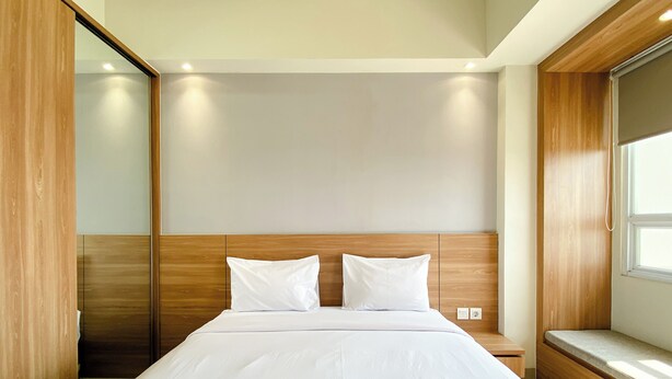 Een hotelkamer met een groot bed, een houten hoofdbord en een raam.
