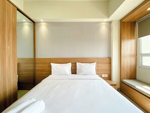 Habitación de hotel con una cama grande, cabecero de madera y una ventana.