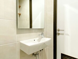Un baño con un lavabo blanco, un espejo y una puerta.