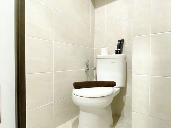 Un baño con inodoro, ducha y soporte para papel higiénico.