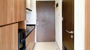 Een smalle keuken met houten kastjes, een roestvrijstalen spoelbak en een gesloten deur.