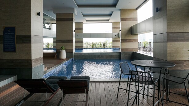 Un área interior de piscina moderna con vistas a la ciudad, suelo de madera y zonas de estar.