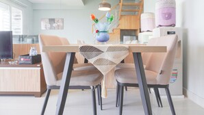 Un comedor moderno con una mesa de madera, sillas color beige y un jarrón decorativo con flores.
