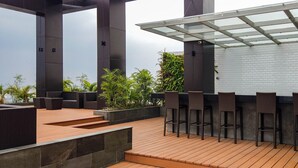 Terraza al aire libre con zona de bar, asientos y jardineras.