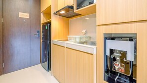 Een moderne keuken met houten kastjes, een inbouwmagnetron, een koffieapparaat en een koelkast.