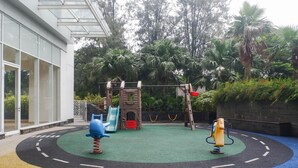 A playground with a slide, swings, and a climbing structure. - Exclusive And Spacey 3Br At Grand Sungkono Lagoon Apartment (Surabaya)