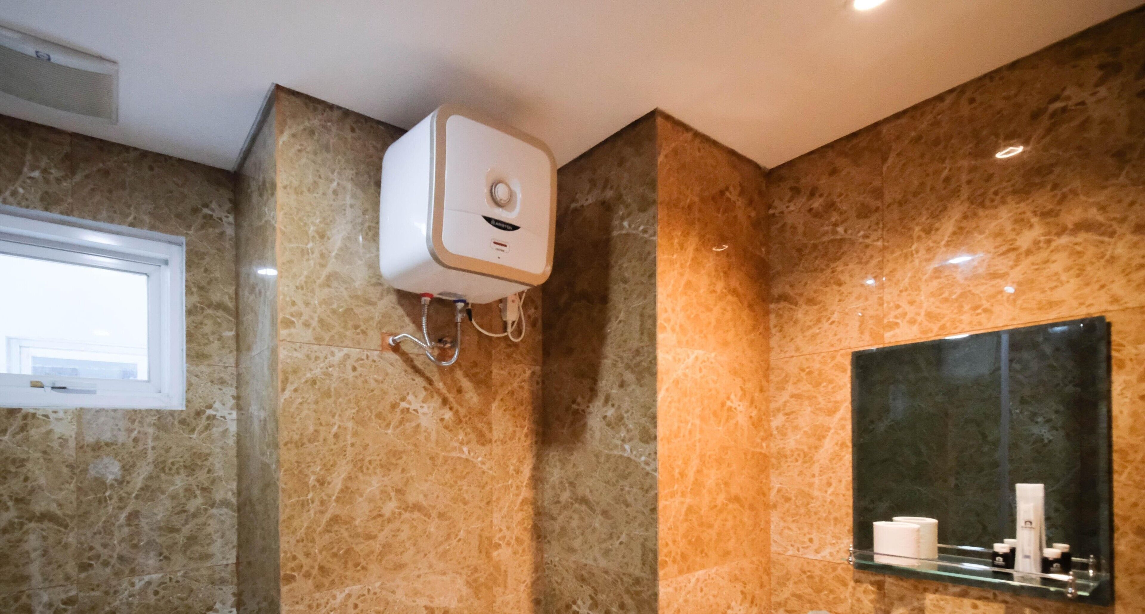 A bathroom with a marble wall, a mounted air purifier, a window, and a mirror with toiletries.