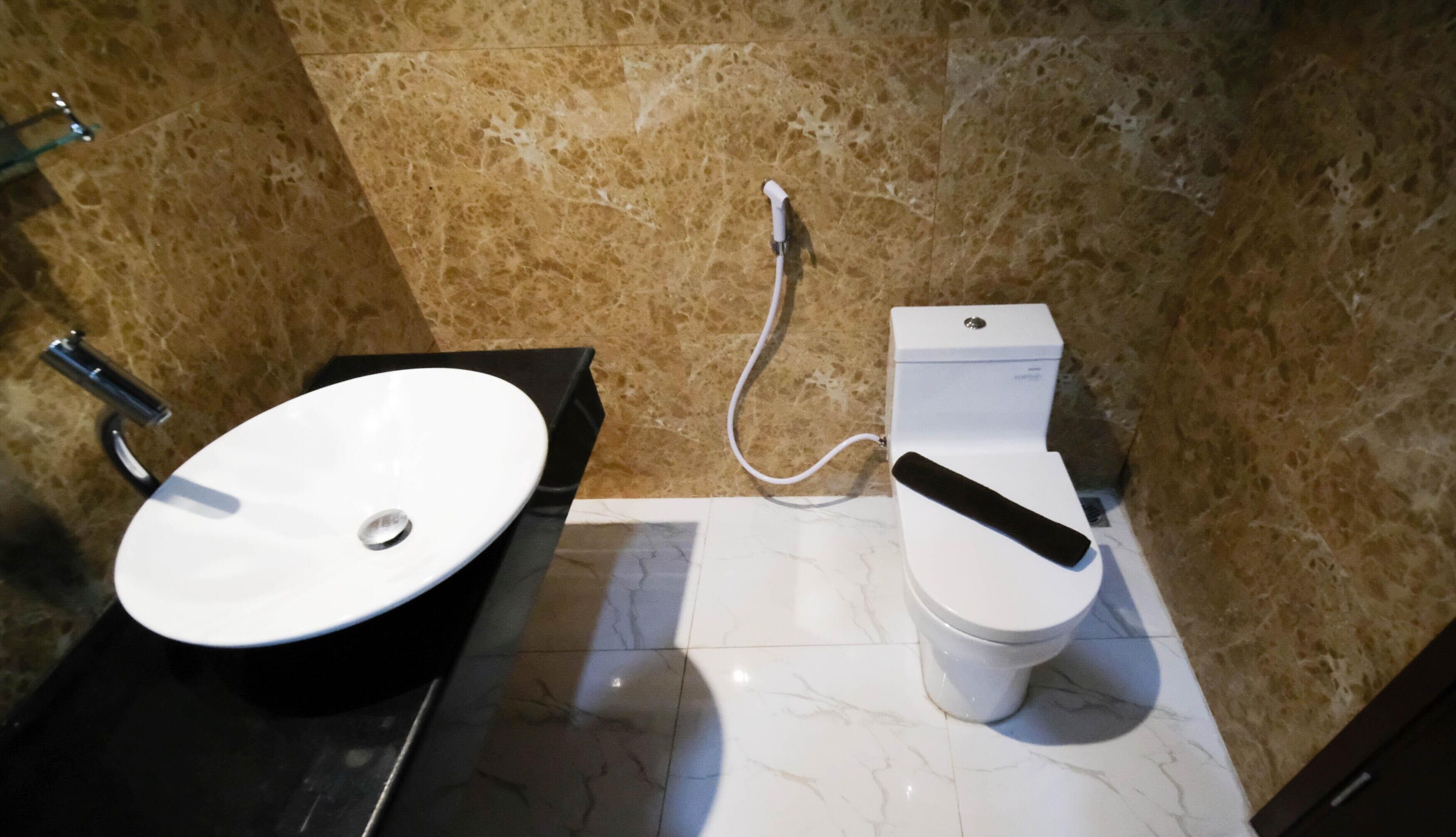 Une salle de bain avec un lavabo blanc, des toilettes et un sol en marbre.