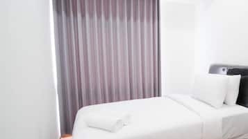 A hotel room with a bed, a window with curtains, and a headboard.