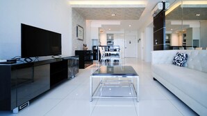 Ein modernes Wohnzimmer mit Flachbildfernseher, einem Glastisch und einem weißen Sofa.
