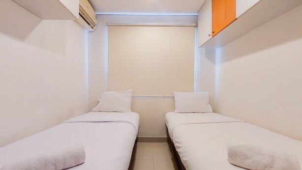 A small, clean room with two single beds, a wooden shelf, and a ceiling light. - Comfort And Cozy Stay 2Br Paramount Skyline Apartment (Gading Serpong)