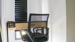 A chair with a mesh backrest and armrests, positioned in front of a window with blinds. - Simply Look And Comfy Studio Sayana Bekasi Apartment (Tarumajaya)